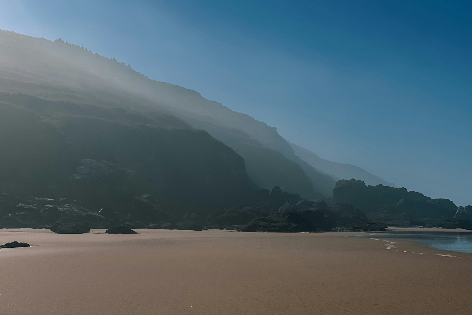 Sandy Atlantic beach backed by green hills in Galicia