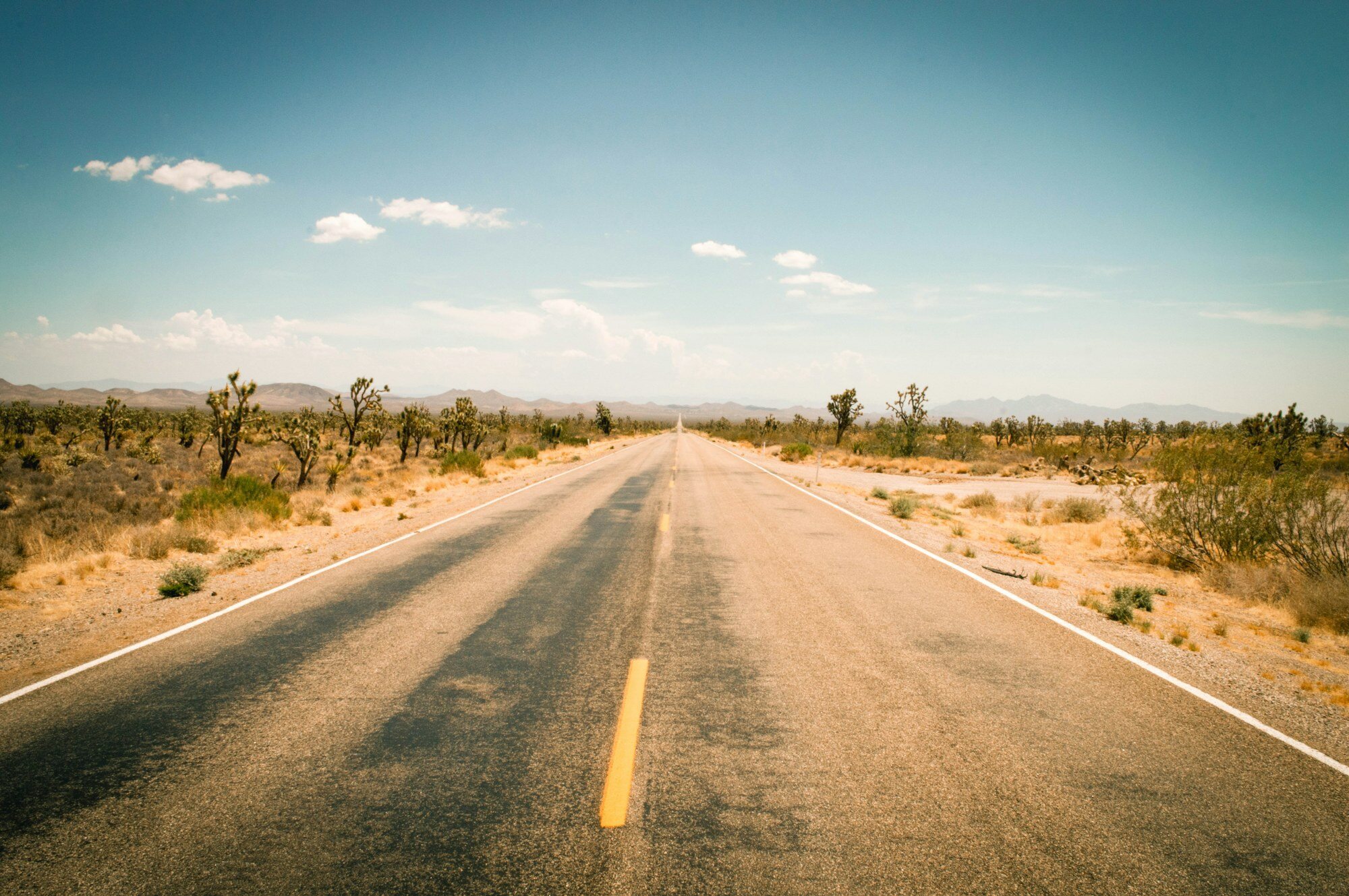 Empty desert highway stretching through Arizona landscape with clear blue sky
