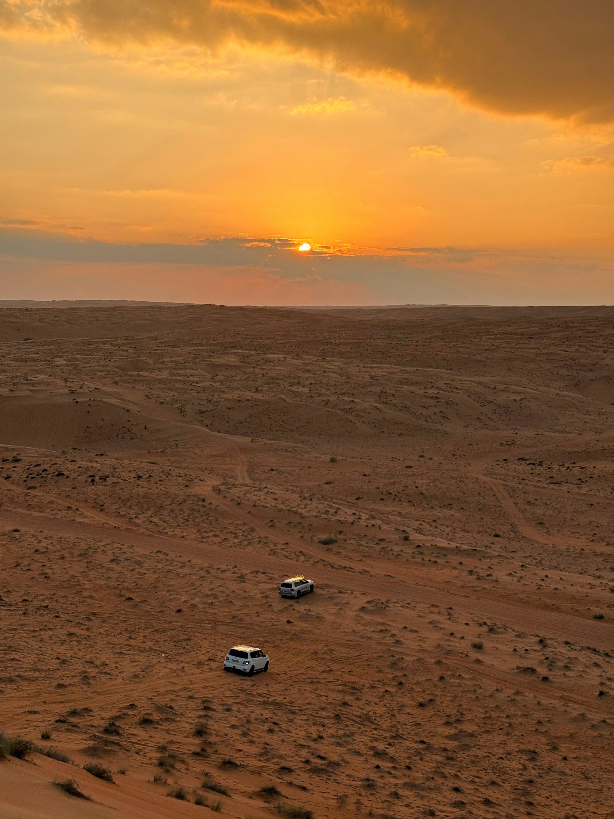 Geländewagen überqueren bei Sonnenuntergang die Dünen der Wahiba Sands im Oman