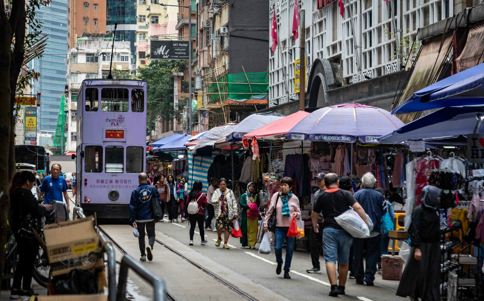 Tramway à deux étages circulant dans un marché de rue animé de Hong Kong