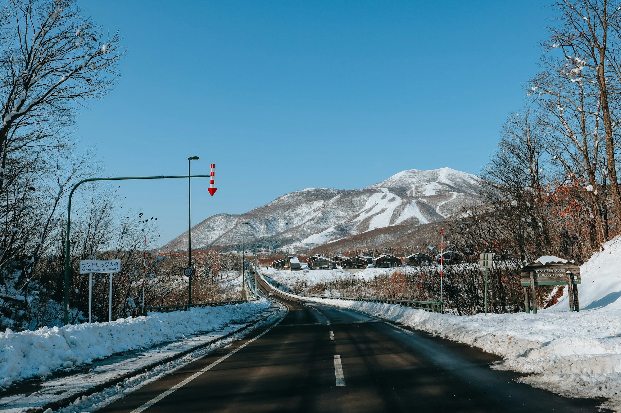 Gray concrete mountain road leading to snow-covered peaks in Hokkaido Japan