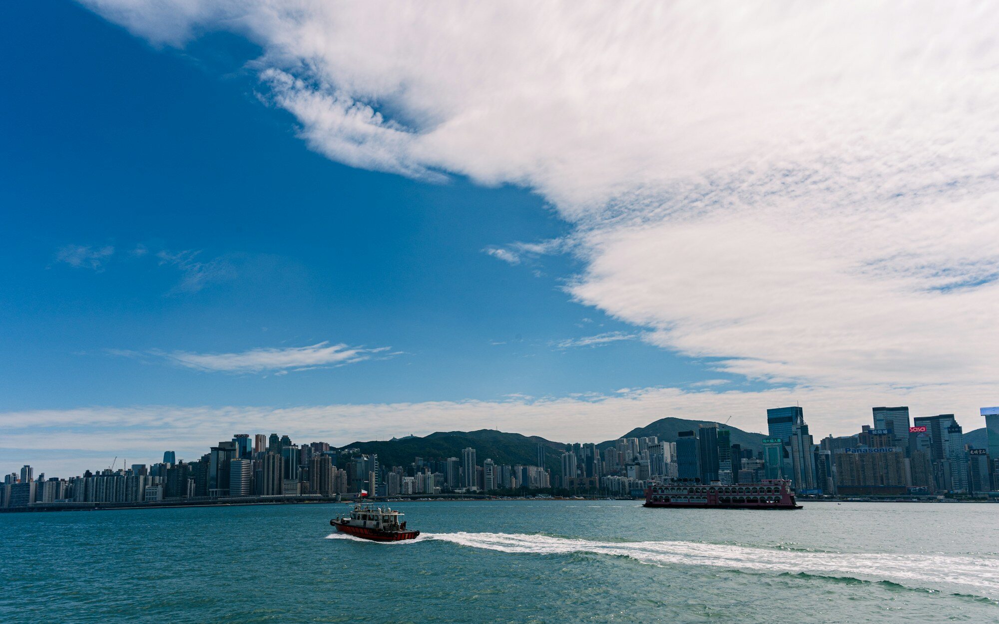 Boote auf dem Victoria Harbour mit der Skyline von Hongkong im Hintergrund