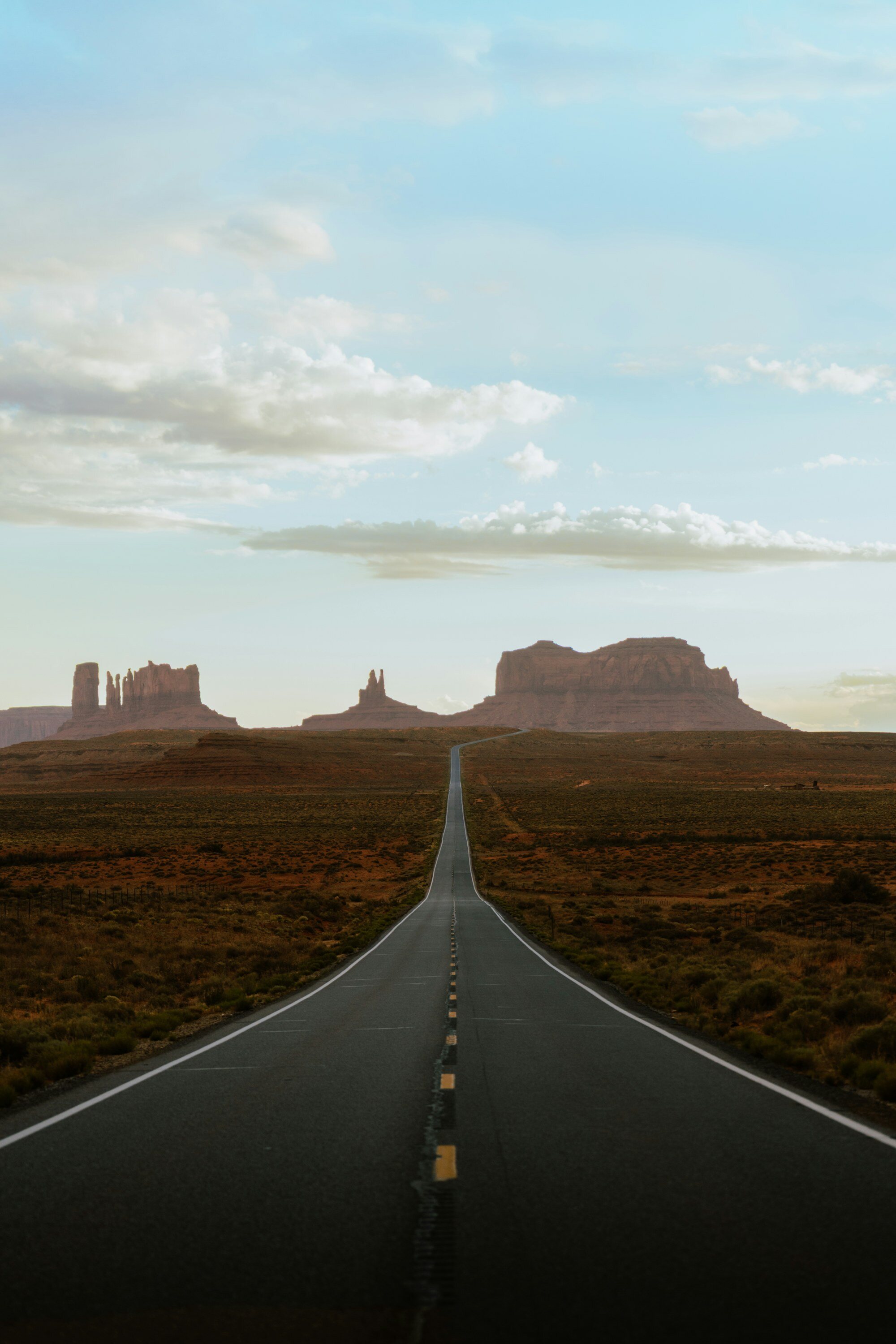 Carretera desértica recta que atraviesa Monument Valley al atardecer